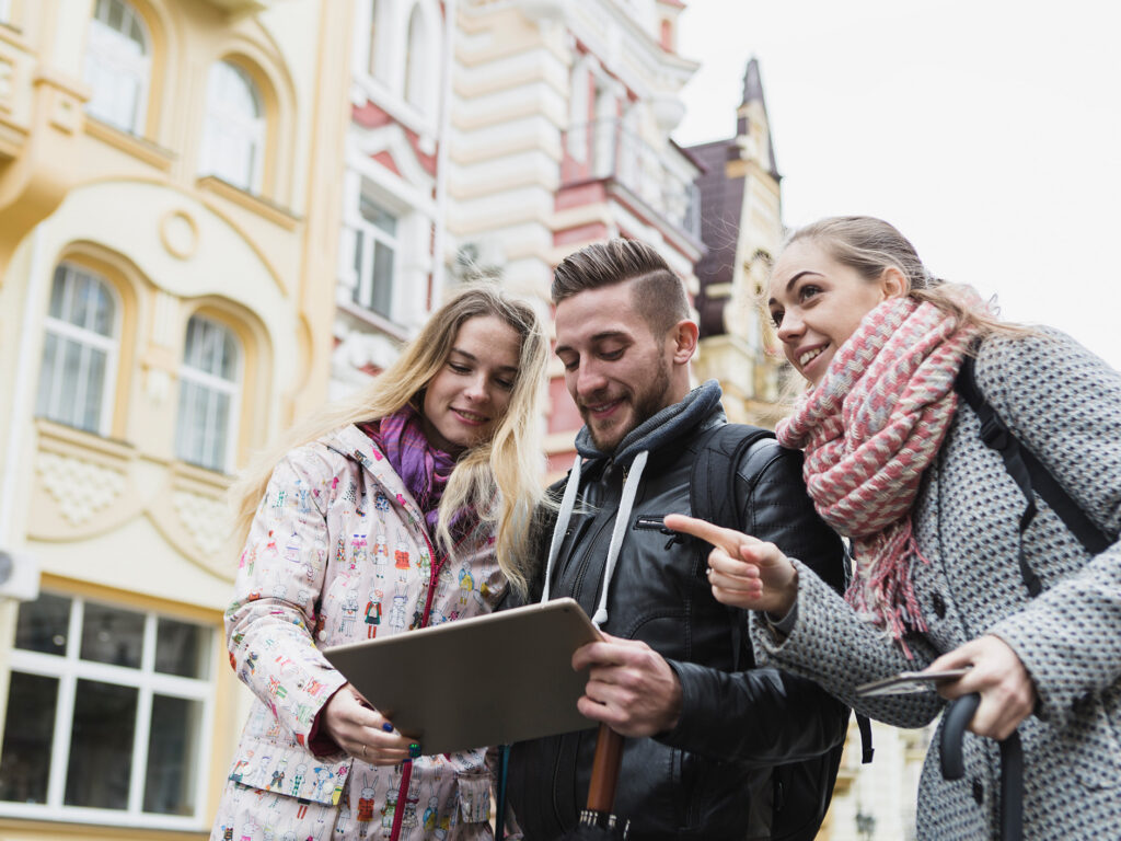 Imagebilde auf der Seite mit Angeboten: Gruppe von Jugendlichen welche in der Stadt unterwegs sind und auf ein Tablet schauen